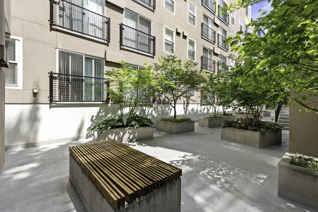 a courtyard with a wooden bench and trees in front of an apartment building a courtyard with a wooden bench and trees in front of  Sir Gallahad Apartment Homes, Washington, 98004